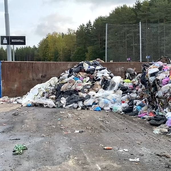 En hög med soppåsar innehållande restavfall men även matrester mellanlagras på en betongplatta inne på Sänkmossens avfallstation i Fagersta.