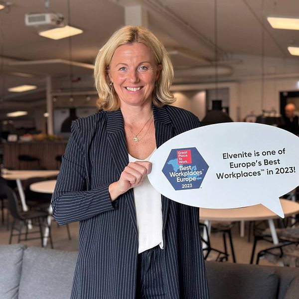 Leende kvinna håller upp skylt med prisutmärkelse