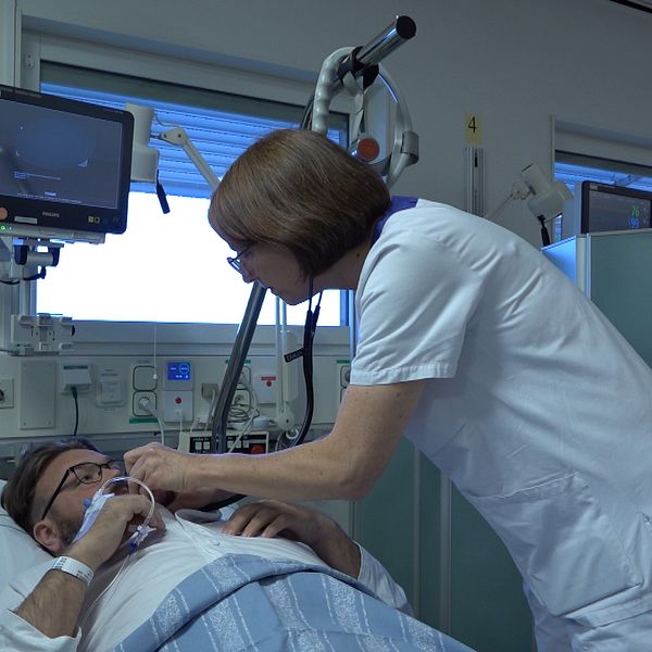 En kvinnlig läkare vårdar en patient som ligger i sängen på ett sjukhus.