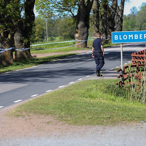 Bild av polis som går med ryggen till vid en skylt med ortsnamnet Blomberg på.