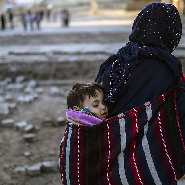 En kvinna bär på sitt barn och vandrar förbi barrikaderna i staden Nusaybin i sydöstra Turkiet.