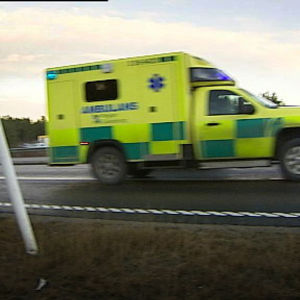 ambulans kör längs väg med skog bakom