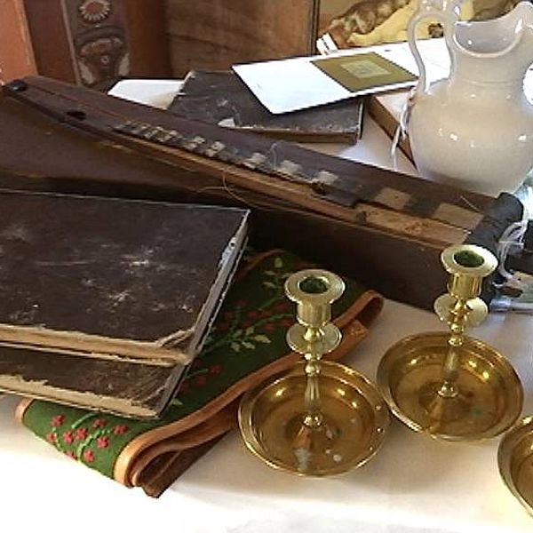 Antika föremål som ljusstakar och kyrkoskrifter på ett bord i Ytterhogdals hembygdsgård