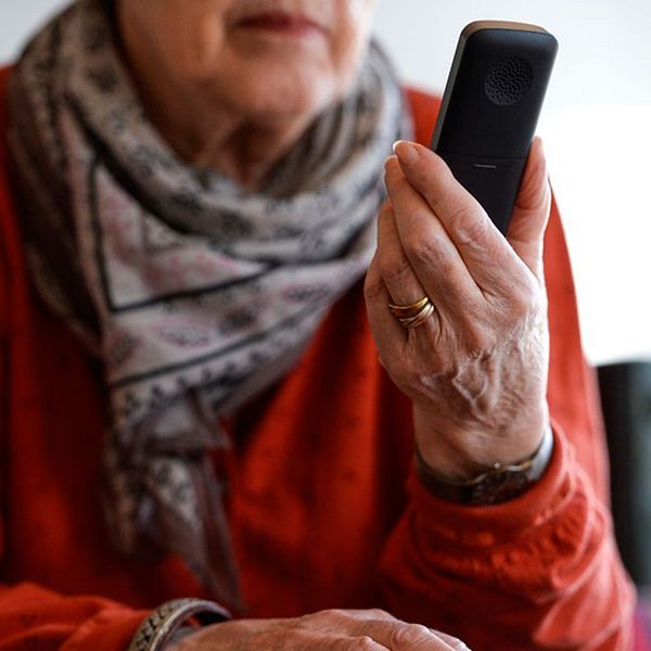 En äldre person med en telefon i handen.