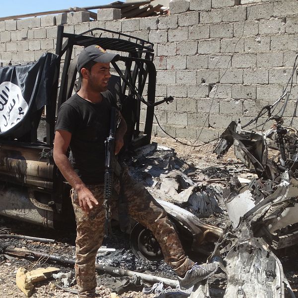 Irakisk soldat vid ett utbränt fordon som tillhört IS. Foto:TT