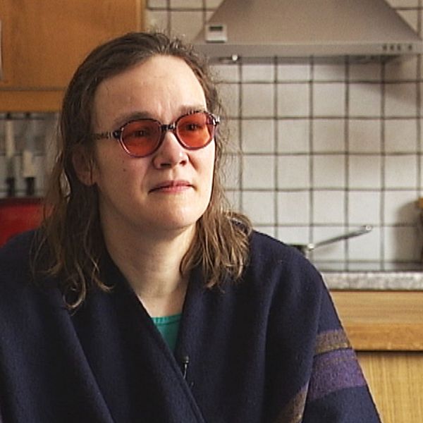 En kvinna med mörkt hår med röda solbrillor på i sitt kök.
