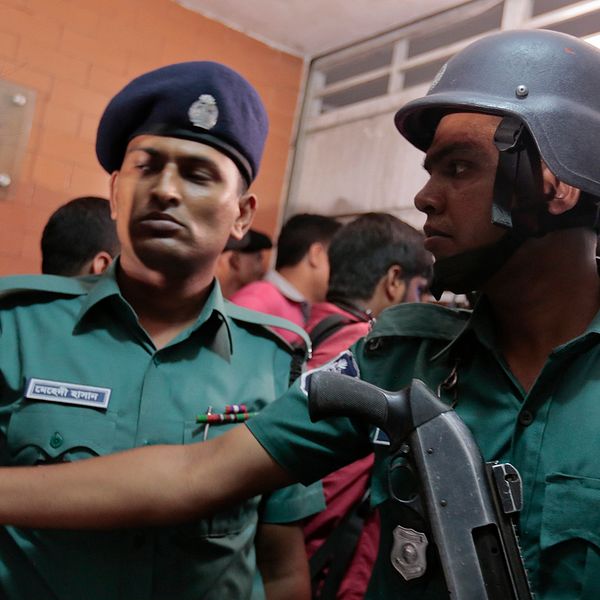 Bangladeshisk polis utanför lägenheten i Dhaka där två män mördats.