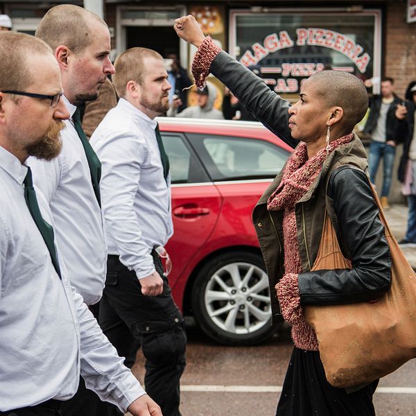 Kvinna står med uppsträckt arm framför första Nordiska Motståndsrörelsen, under första maj i Borlänge 2016.
