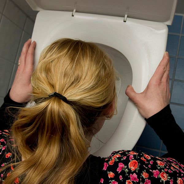 Kvinna hukar över toalett.