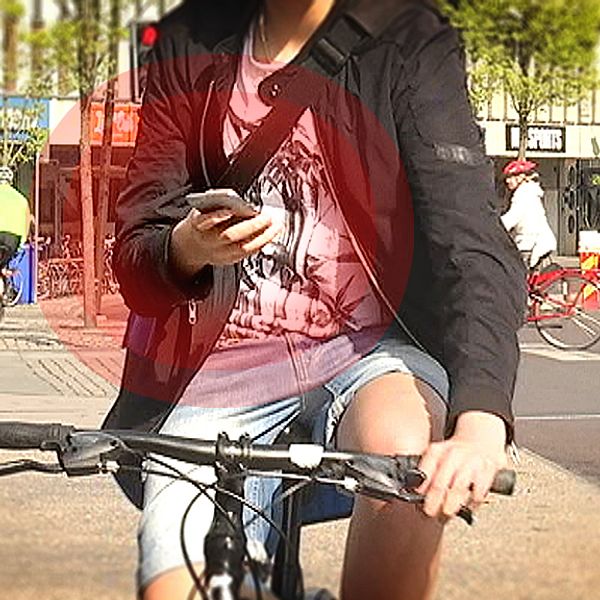 Cyklist tittar på mobilen medan han cyklar.