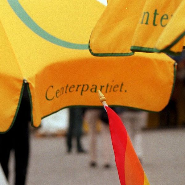 Centerpartiets logotyp på parasoll och en pride-flagga