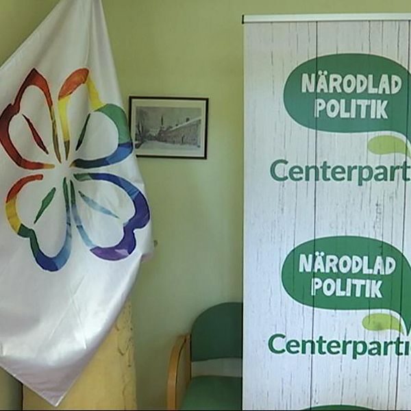 Centerpartiet logotyp och en flagga med partiets klöver i regnbågsfärger