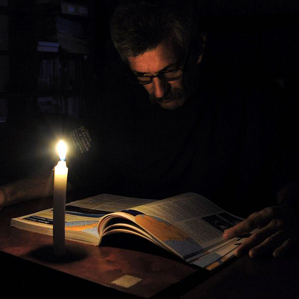 En man läser i skenet av stearinljus under ett av många elavbrott i Venezuela.