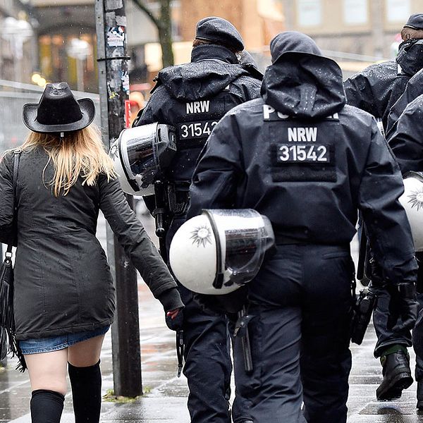 Kvinna tillsammans med poliser i Tyskland.