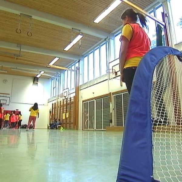 Skolidrottshall med barn som spelar innefotboll.