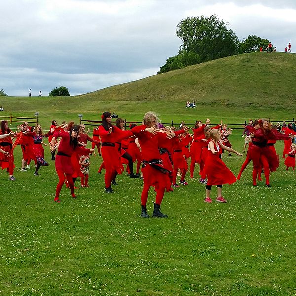 Ett hundratal rödklädda Kate Bush-fans dansar till tonerna av Wuthering heights med kungahögarna i Uppsala i bakgrunden.