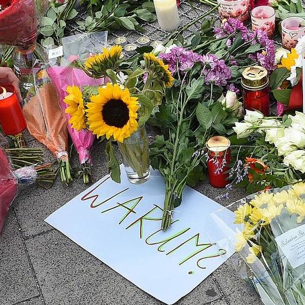 Blommor och en skylt med texten: ”Varför?” i närheten av shoppingcentret i München där skottdramat ägde rum på fredagen.