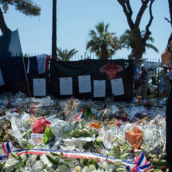 Polis framför nedlagda blommor i Nice.