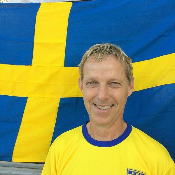 Olof Olsson står framför svenska flaggan.
