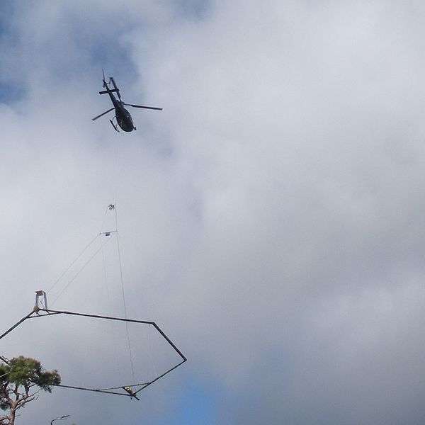 En helikopter med en stor ram som hänger under.
