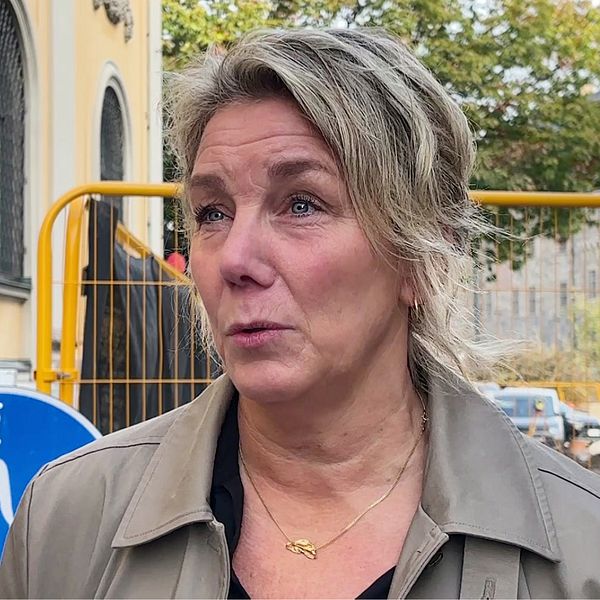 Pia Norstedt utomhus vid byggarbetsplats i Örebro, trafikskylt synlig i bakgrunden.