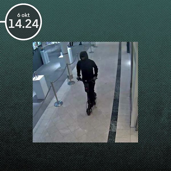 Övervakningsbild visar en maskerad person i mörka kläder på en bank, tidpunkt 14.24 anges.