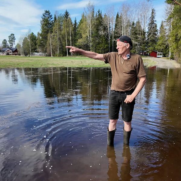 Man står i stövlar i vatten och pekar.