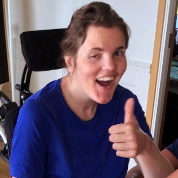 Anna Holmlund sitter i en rullstol och gör tummen upp.