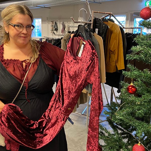 Kvinna håller upp en röd klänning i en butik.