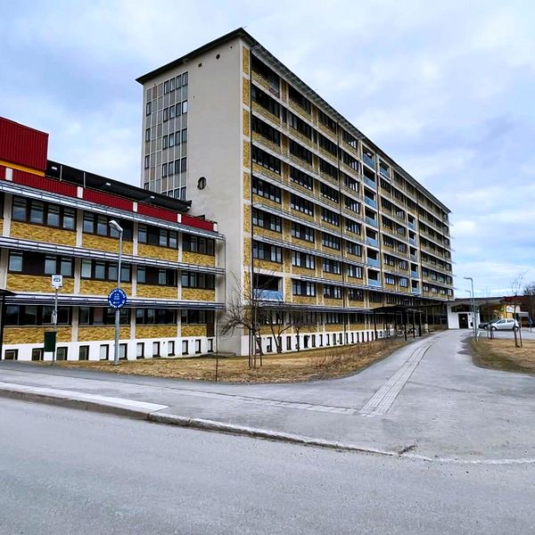Sollefteå sjukhus. Framsidan visar en asfalterad väg som leder till byggnaden, med parkeringsplatser synliga i bakgrunden.