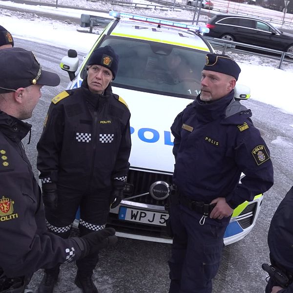 Grupp av svenska och norska poliser med polisfordon i bakgrunden. Snö och is syns på marken