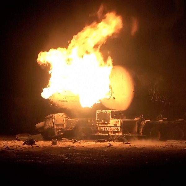Militärfordon i fullt brandförlopp under natten.