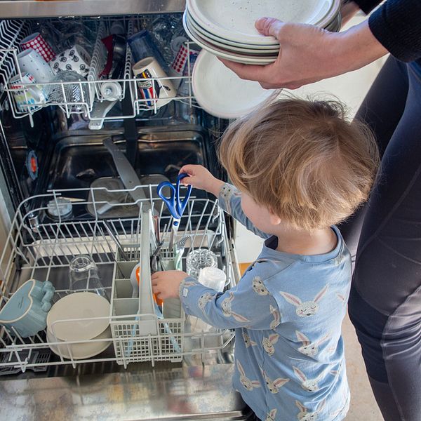 Förälder och barn hjälps åt att plocka ur diskmaskin.