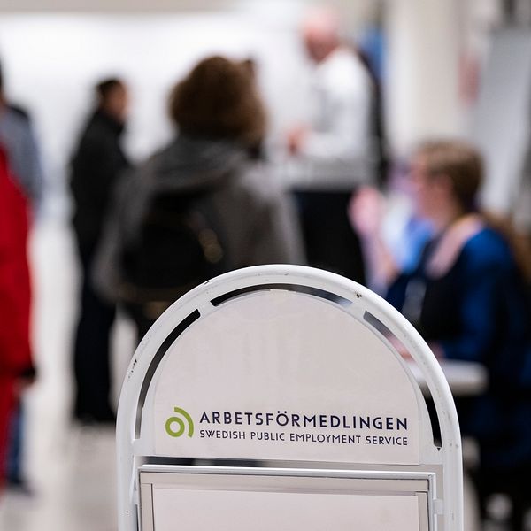 En Arbetsförmedlingen-skylt och personer i bakgrunden