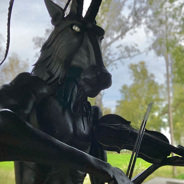 En järnstaty föreställande en bock som står på bakbenen och spelar fiol.
