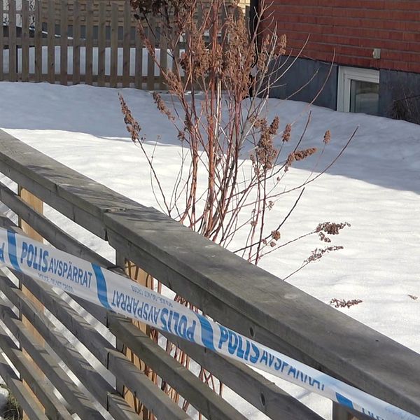 Snötäckt mark avspärrad med polisband vid ett hus.