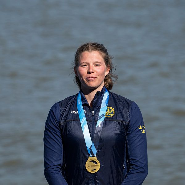 Kanotisten Melina Andersson står framför vatten med en medalj runt halsen .