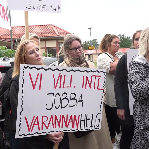 Flera kvinnor står med plakat i händerna. På plakatet i bild står det ”vi vill inte jobba varannan helg”.