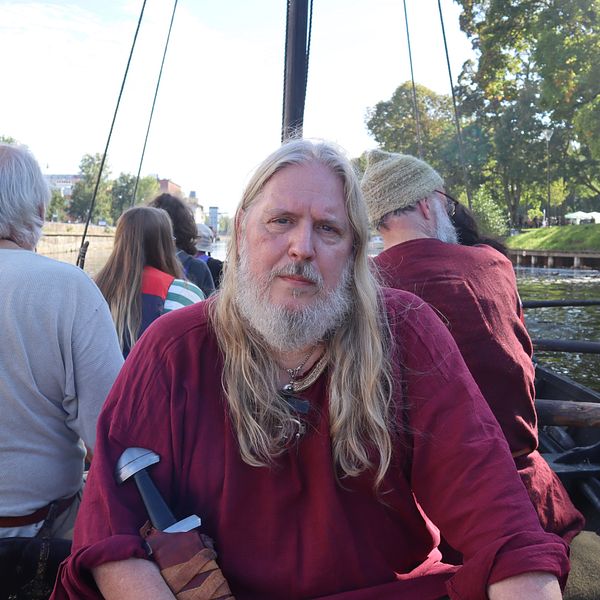 Arkeologen Anders Ekberg tittar in i kameran sittandes på vikingabåten Sefnir.