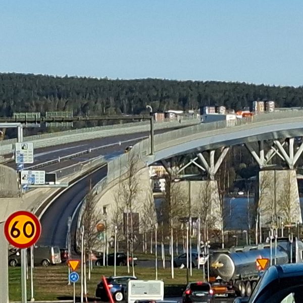 Motorvägsbro med 60-skylt, bilar i förgrunden och skog i bakgrunden.