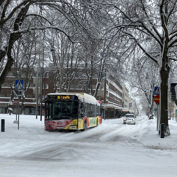 En snötäckt gata med en buss som står stilla med texten ej i trafik.