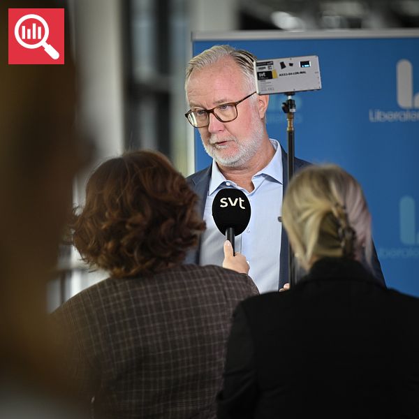 Journalister intervjuar en person framför Liberalernas banner.