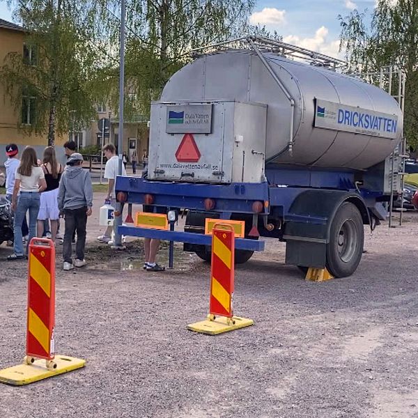 en vattentank och flera personer som står runt omkring.