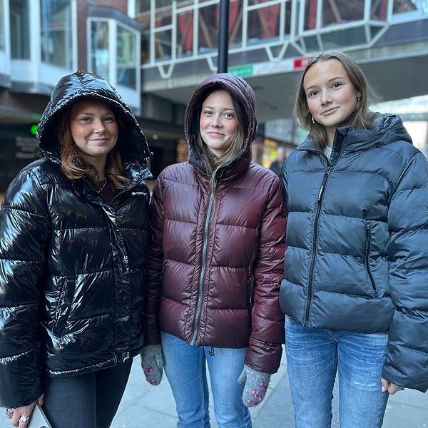 Tre tjejer i 18-årsåldern, två med svarta jackor och en i vinröd, inne i centrala Västerås.