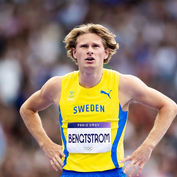 Svensk atlet i gult och blått sportställ med namnet ”BENGTSTRÖM” synlig på bröstet, står med en fokus på tävlingen bakom honom. Grottade människor och en arena kan skymtas i bakgrunden.