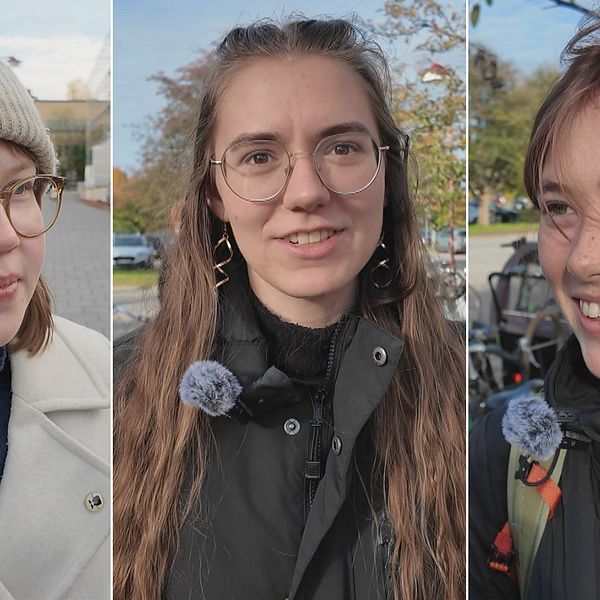 Tre personer är fotograferade utomhus, klädda i olika jackor och med mikrofoner fästa vid sina kläder. Den första personen bär en vit mössa och en ljus jacka, den andra har på sig en svart jacka med en mörk tröja under, och den tredje personen har en svart jacka med detaljer i grönt och guldörhängen. Bakgrunden visar en klar himmel och del av en stadsmiljö.