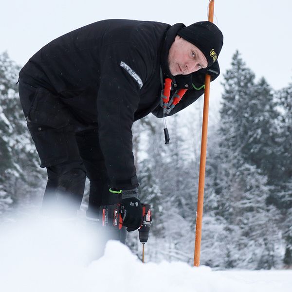 Johan Hedman, arbetsledare friluft Uppsala kommun, borrar i isen