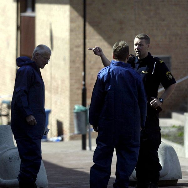 En poliskonstapel pratar med två män på gatan.