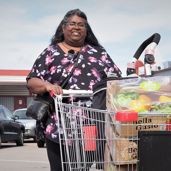 Kvinna med matvagn framför affär