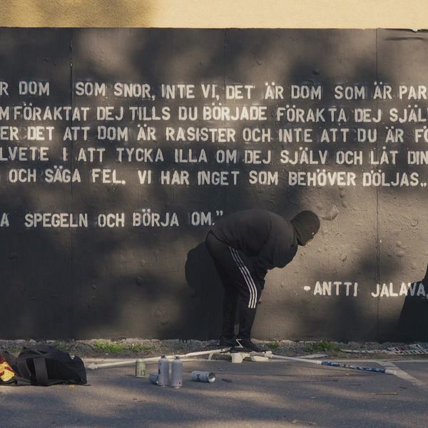 två graffitikonstnärer färdigställer ett citat på väggen
